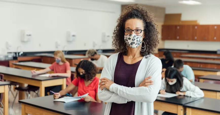 A happy teacher ready to start the new school year with masks. 