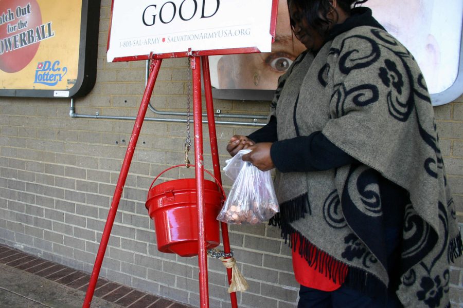 A picture of a donation being made to the Salvation Army kettle.    