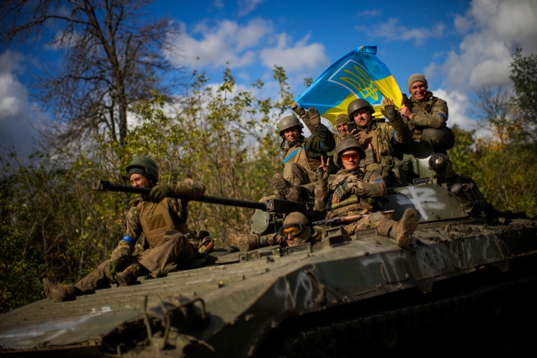 Ukrainian soldiers sit on an armoured vehicle as they drive on a road between Izyum and Lyman in Ukraine, on October 4, 2022