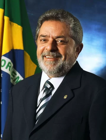 Lula Da Silva, standing in front of the Brazilian flag.