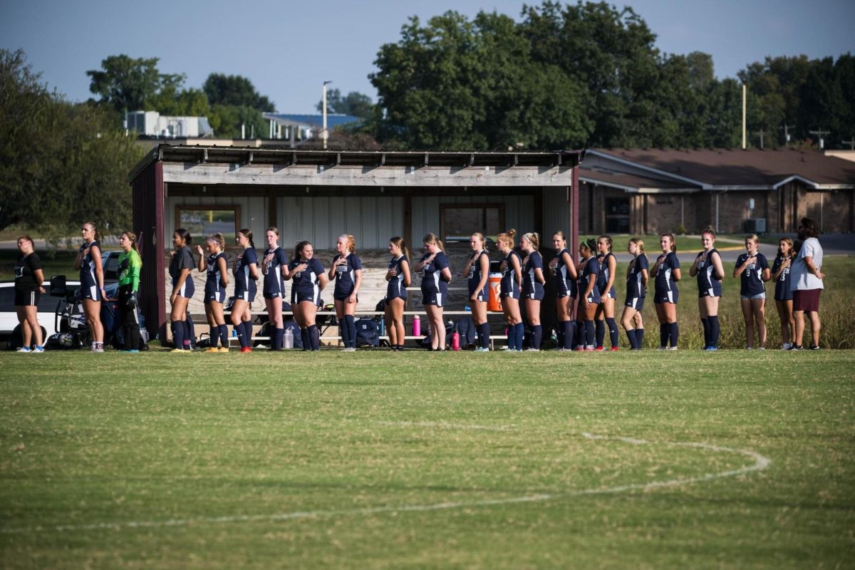 A picture of the girl's soccer team standing for the national anthem